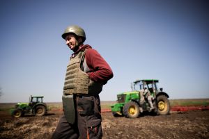 Ukrainian farmer, wearing body armour and helmet, works at the topsoil in a field, amid Russia's invasion of Ukrain
