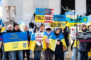 People with signs saying "Pray for Ukraine stop war" "Stand together" and "Stand with Ukraine" at a Stand With Ukraine rally at the Lincoln Memorial.