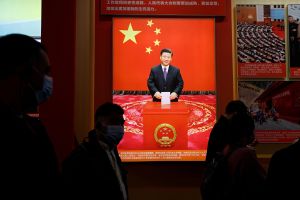 Visitors walk past an image of Chinese President Xi Jinping holding a ballot, at an exhibition titled "Forging Ahead in the New Era" during an organised media tour ahead of the 20th National Congress of the Communist Party of China