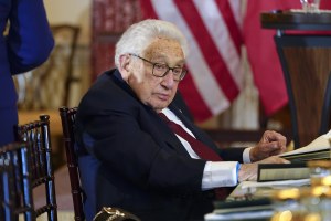 Henry Kissinger sits at a table