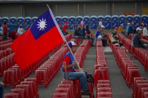 A voter holds a Taiwan flag as he waits for the start of a campaign rally