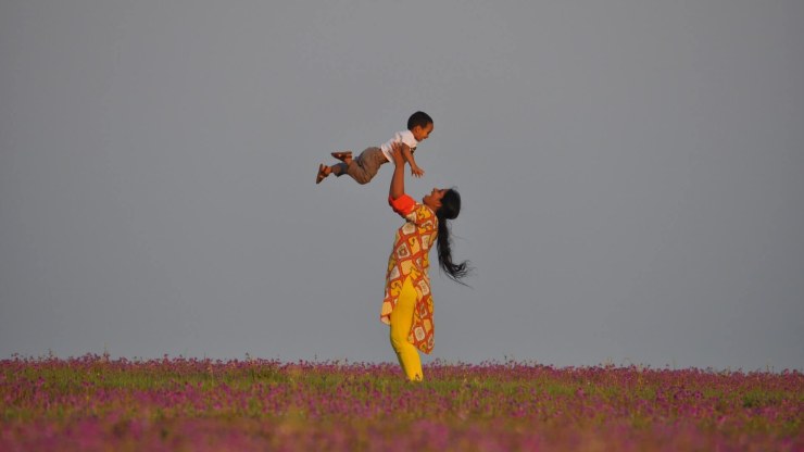 A woman in India tosses her child in the air.