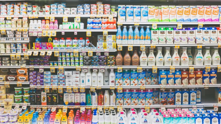 A shelf of milk and alternative milks at a grocery store.