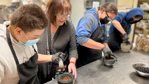 Executive Director of the Cheyenne River Youth Project (CRYP), Julie Garreau, works with three students participating in the CRYP Garden Club as they learn how to grind berries.