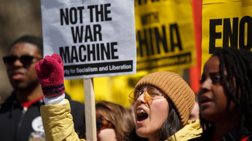 a protester holds a sign that says "not the war machine"