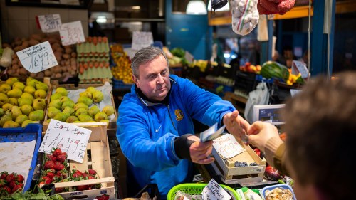 József Varga, owner of a grocery in Budapest's Grand Market Hall, gives change to a customer.