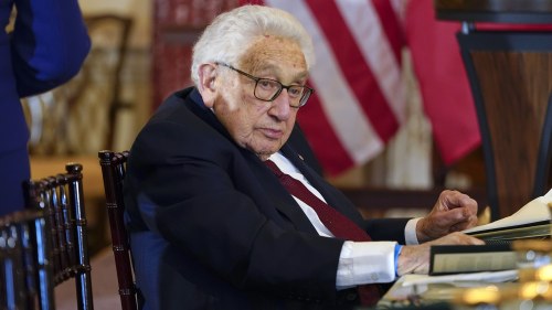 Henry Kissinger sits at a table