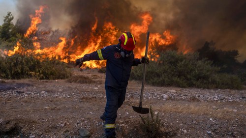 A firefighter leaves as the flames approaching him during a wildfire in Vati village, on the island of Rhodes, southeastern Greece. A third successive heat wave in Greece pushed temperatures back above 40 degrees Celsius (104 degrees Fahrenheit) across parts of the country Tuesday following more nighttime evacuations from fires that have raged out of control for days.  