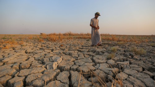A fisherman walks across a dry patch of land in the marshes in Dhi Qar province, Iraq.