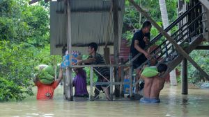 People carry food and supplies up stairs during a flood in Southeast Asia