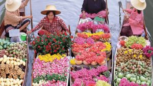 People with crates of fruits, vegetables, and flowers travel by boat