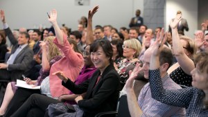 An audience at a Council event raising their hands