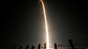 People watch as a SpaceX Falcon 9 rocket, topped with the Crew Dragon capsule, is launched carrying four astronauts on the first operational NASA commercial crew mission at Kennedy Space Center