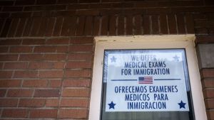 sign reading we offer medical exams for immigration in front of brick wall