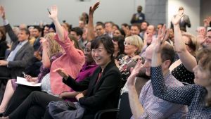 An audience at a Council event raising their hands