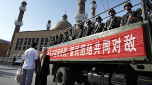 An ethnic Uighur couple waits as a truck loaded with Chinese paramilitary police goes by in China's Xinjiang Autonomous Region 