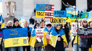 People with signs saying "Pray for Ukraine stop war" "Stand together" and "Stand with Ukraine" at a Stand With Ukraine rally at the Lincoln Memorial.