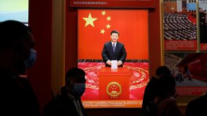 Visitors walk past an image of Chinese President Xi Jinping holding a ballot, at an exhibition titled "Forging Ahead in the New Era" during an organised media tour ahead of the 20th National Congress of the Communist Party of China