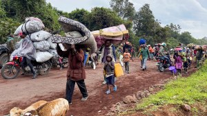Congolese civilians carry their belongings as they flee near the Congolese border with Rwanda after fightings broke out in Kibumba, outside Goma in the North Kivu province of the Democratic Republic of Congo