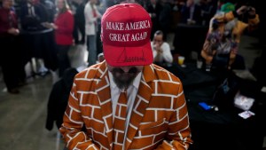A Trump supporter wears a red Make America Great Again hat and a suit with a brick wall pattern