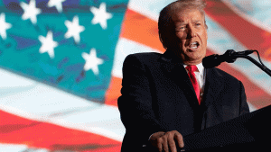 Donald Trump speaks in front of an American flag graphic