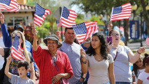 People of various ages wave American flags