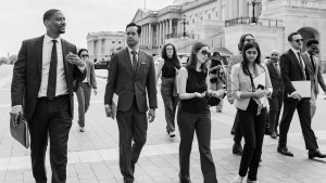 A black and white photo of people walking in front of the US Capitol